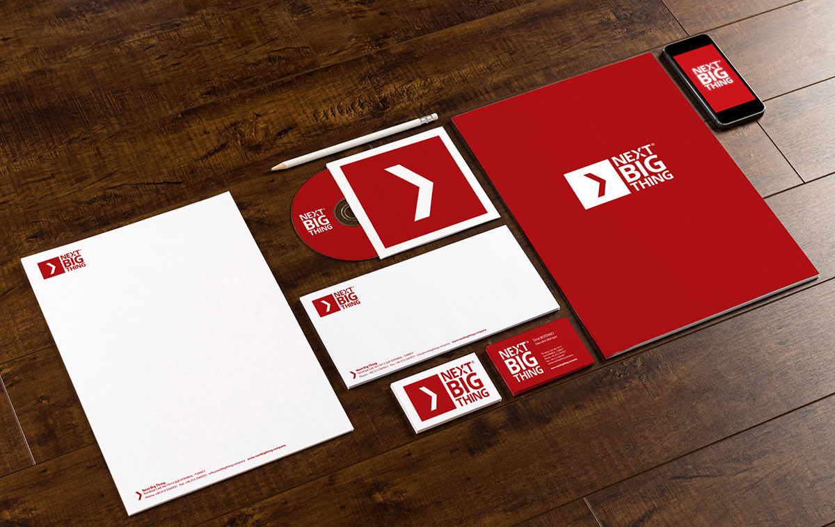 Next Big Thing stationery in red and white on a timber desk